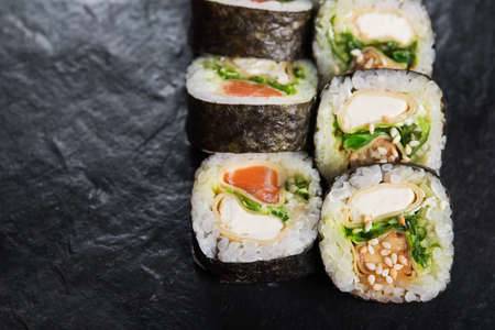 Closeup of sushi roll with salmon on a black slate background. japanese food menuの写真素材