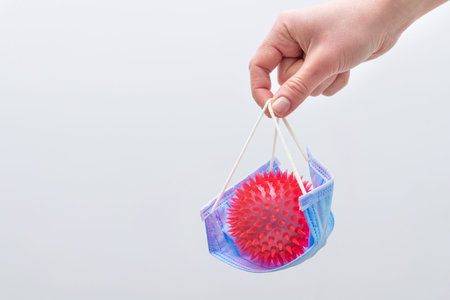 Doctor is holding a red molecule or model of coronavirus in her hands on a background. Concept of...