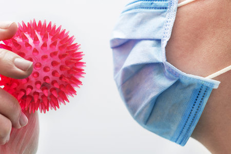 Doctor is holding a red molecule or model of coronavirus in her hands on a background. Concept of...