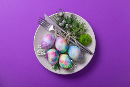 Served Easter plate with eggs and flowers on a trend violet color background.