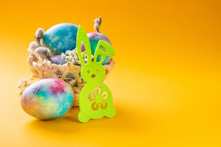 Easter concept with rabbit and eggs in basket on a yellow background. copyspace for text