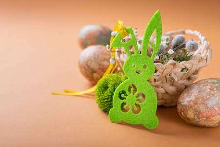 Easter eggs with flowers and decorative bunny on orange background