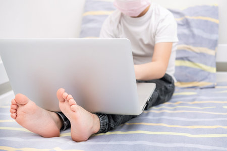 Boy doing homework at home with a laptop on quarantine.