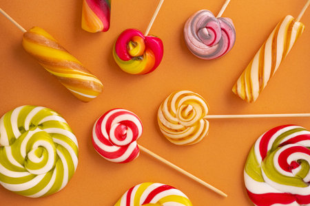 Colored sweet lollypops on orange background. Summer candy food concept.