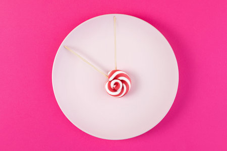 Time to start diet and give up sweet harmful, high-calorie foods. Plate with clock hand candy on...