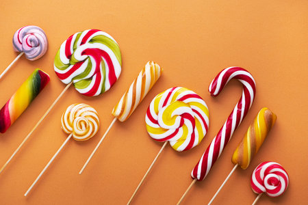 Colored sweet lollypops on orange background. Summer candy food concept.の写真素材