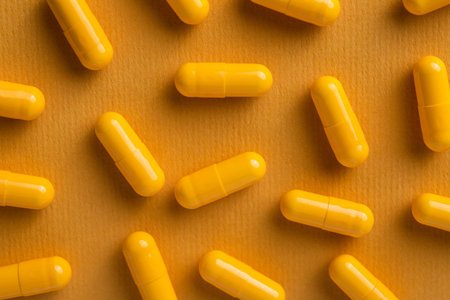 Yellow vitamin pills in capsule on a background. top view