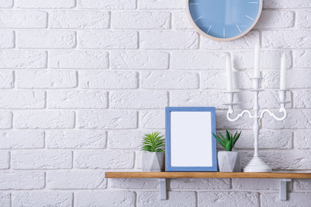 Blue wooden frame with empty photo. Green succulents plants on wooden board. Scandinavian room. Brick white wall background.の写真素材