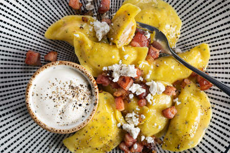 Delicious dumpling with cheese, fried bacon and sour cream in plate. Top view.の写真素材