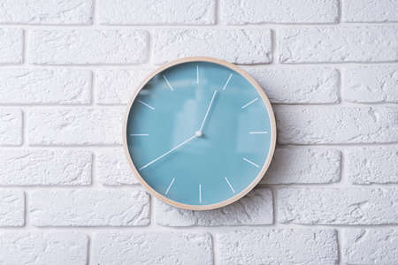 Wooden clock in minimalistic style on a white brick wall. Lunch time. Scandinavian style in the room.の写真素材