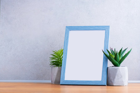 Blue wooden frame with empty photo. Green succulents plants on wooden board. Scandinavian room.