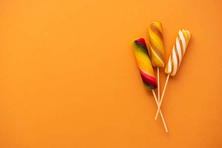 Colored sweet lollypops on orange background. Summer candy food concept.の写真素材