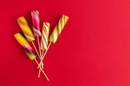 Sweet colorful lolly pops on red background. Tasty color food concept. Top view.の写真素材