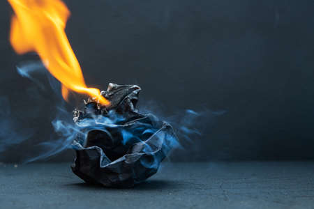Crumpled paper ball burns with fire on a black background. Bad idea. Failure.の写真素材