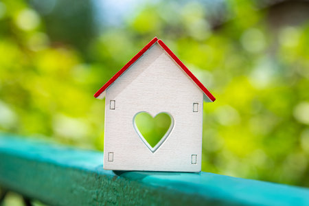 A small cozy house with heart for a family stand in green area park. Property insurance. Real estate purchase.の写真素材