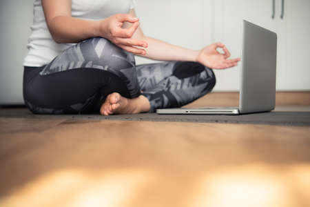 Woman doing yoga at home sitting on the floor in padmasana lotus position in the kitchen.の写真素材