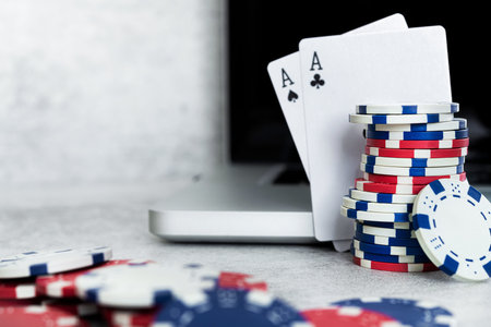 Cocnept of poker online games, chips and cards with laptop on gray background.