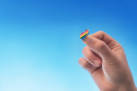 Multicolored icon in the shape of a heart, the colors of the lgbt community, hold in a hand against...