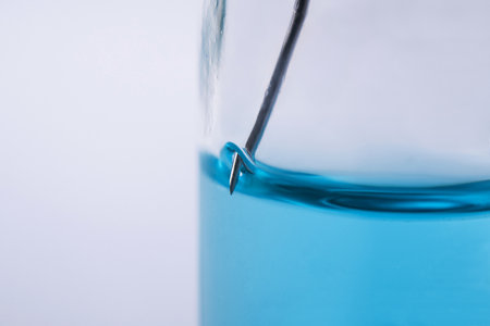 Closeup of glass bottle with coronavirus medication. Laboratory studies of the vaccine. White background table. Needle and air bubbles. Vaccine development.の写真素材