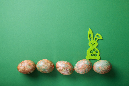 Easter minimal concept with bunny toy and easter eggs on a green background. top view. copyspace.