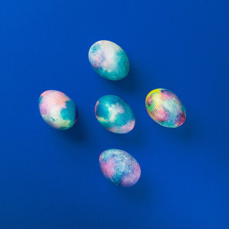 Happy Easter concept with colored eggs on a blue background. top view. minimal, flat lay