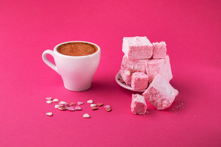 Cup of coffee with turkish sweets on a pink background. Snack for a girl. rahat lukum.の写真素材