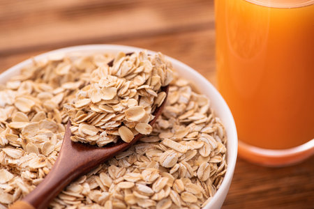 Oatmeal grain in a white bowl on wooden table with carrot juice glass healthy diet breakfast...