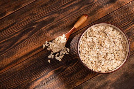 Bowl with oatmeal flakes on a wooden background. diet healthy breakfast concept. top view.の写真素材
