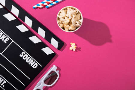 Popcorn cup, movie clapper, 3d glasses on a rose background. film concept.の写真素材
