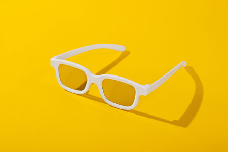 White 3d movie glasses on a yellow background