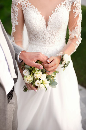 Bride and groom holding hands, wedding roses bouquet. marriage celebration background.の写真素材