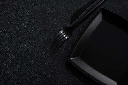 Black tableware knife and fork on a black background. Top view. Copyspace text.の写真素材