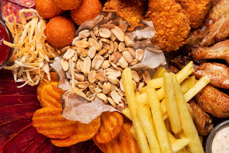 French fries, peanut, cheese balls and chicken wings. beer plate background. top view.の写真素材