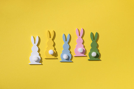 Easter holiday concept with many colored rabbit decor on a yellow background. top view.