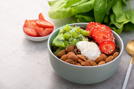 Granola with yogurt, kiwi, almond nuts, strawberry in a bowl on stone table. Healthy Eating.の写真素材