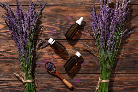 Bottle with lavender oil and a fresh bouquet of flowers on a wooden background. production of perfumes.の写真素材