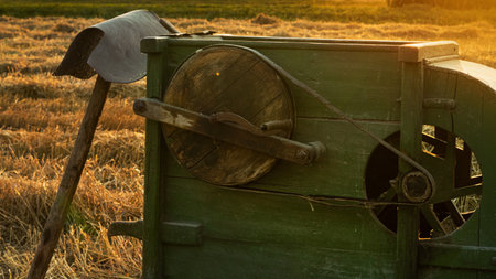 Old retro wheat mill in the field. homemade. home-made device for winnowing grain. summer harvest at sunset.の写真素材