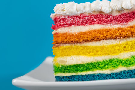 One sweet and tasty rainbow cake dessert on a blue background.の写真素材