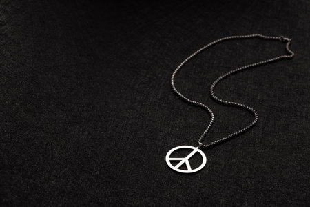 Necklace with a mark of peace on a black old background. Stop war in Ukraine. Anti war concept.の写真素材