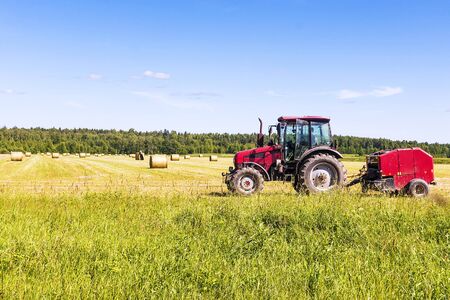 Red tractor in the field on a hayの写真素材