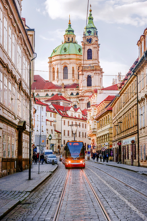 PRAGUE, CZECH REPUBLIC-MAY 17, 2017: A tram on a historic street in Prague against the St. Nicholas Cathedral.のeditorial素材