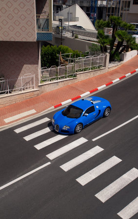 A high angle shot of a blue sport car crossing a pedestrian crossing