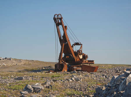 An old rusty broken excavator stands against the background of stonesの写真素材