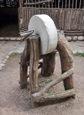 An old manual whetstone (grinding machine) on wooden supportsの写真素材