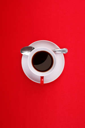 Coffee cup, saucer and spoon on a red backgroundの写真素材