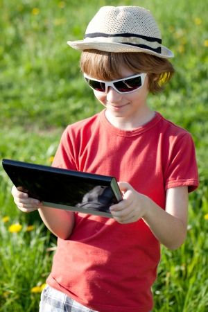 Boy playing with enthusiasm in the Tablet PC on the natureの写真素材
