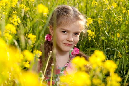 Little girl sitting in the grass and yellow flowersの写真素材