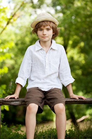 Teenager in a hat and shirt sitting on benchの写真素材