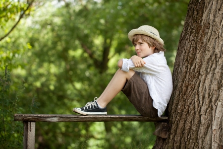Boy sits on a bench and looks awayの写真素材