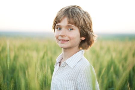 Joyful boy against a wheat field in the eveningの写真素材
